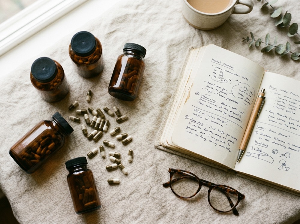 Amber supplement bottles and an open notebook on linen